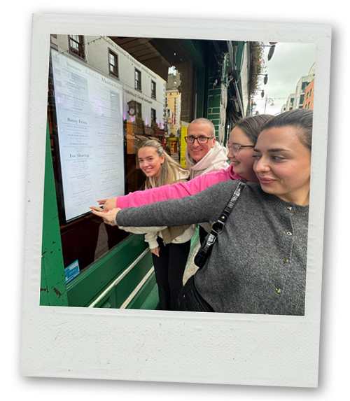 Four members of LNOF staff all pointing to a menu outside a Dublin restaurant