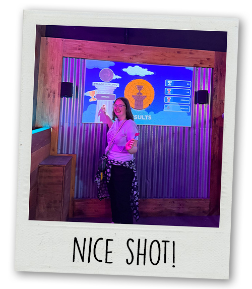 Hannah standing next to a darts board with the caption Nice Shot