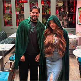 A male and a female member of LNOF staff stood wearing green traitors cloaks in the Tigerlily bar in Edinburgh 