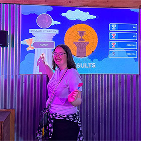  A female member of LNOF staff posing next to a darts board that says Winner 
