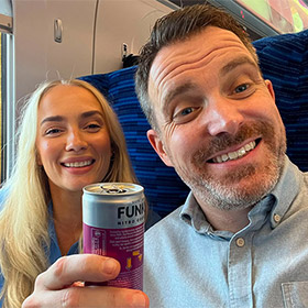  A male and female member of LNOF staff drinking tins of alcohol on a train 