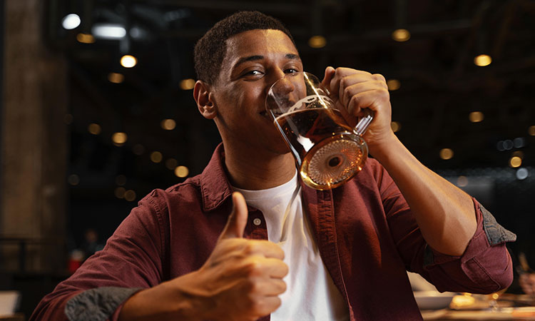 A man drinking a pint and giving a thumbs up