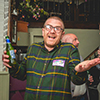  A man with glasses (Adam Cutts, head of sales) and a green checked shirt holding a beer and making a goofy expression. 