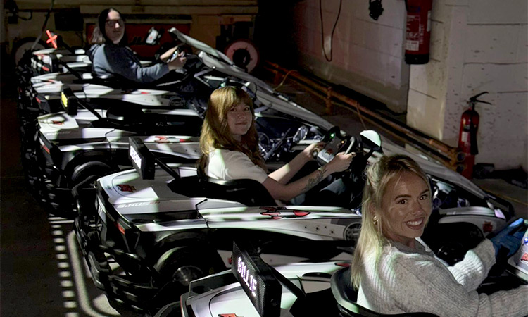 Three female members of LNOF staff sitting in go karts