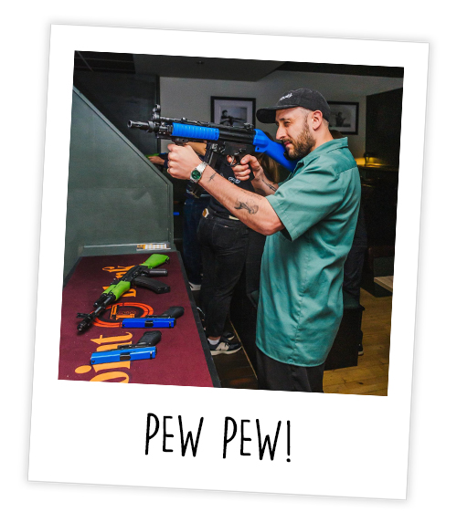A Polaroid of a man who is shooting a virtual reality gun at Point Blank with the caption Pew Pew