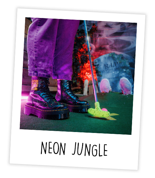 A Polaroid of the bottom half of someone playing mini golf with the caption Neon Jungle 