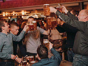 A stag group clinking pints in a pub in Newcastle 
