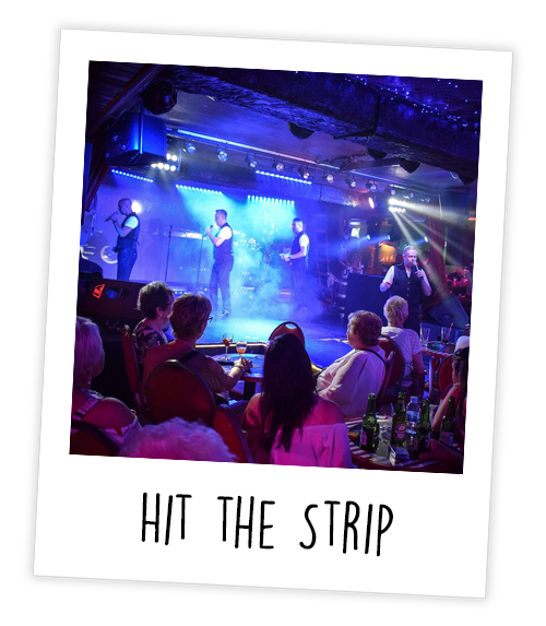 A Polaroid reading hit the strip that is of people watching some men sing in a bar