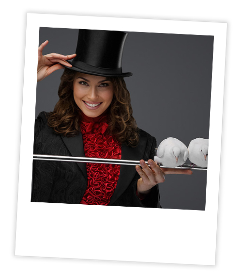 A Polaroid of a woman in a top hat and red jacket who is balancing some birds on a magic wand