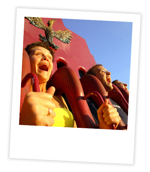 A Polaroid of 3 people on a rollercoaster gripping on to the over shoulder restraints