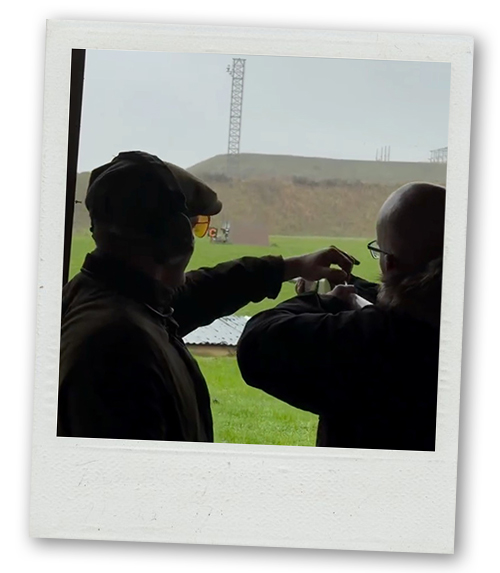 A Polaroid of an instructor showing a man how to do clay pigeon shooting