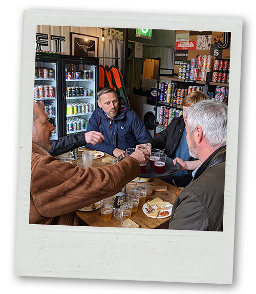A Polaroid of a stag do group sitting in a brewery enjoying a drink