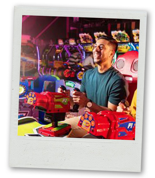 A Polaroid of a man playing an arcade game at Gravity Max