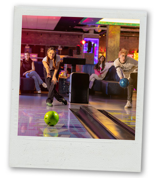 A Polaroid of a man and a woman bowling in lanes next to each other at Gravity Max