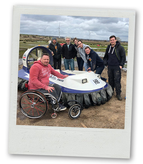A Polaroid of a stag do group posing next to a hovercraft