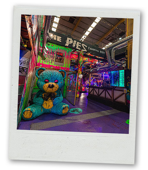 A Polaroid of a mini golf venue which has a massive blue teddy bear art instillation in the entrance