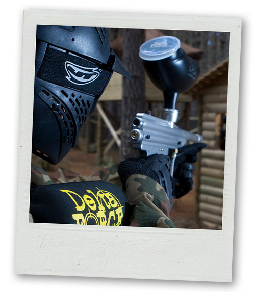 A Polaroid of a man holding a paintball gun in an outdoor paintball arena