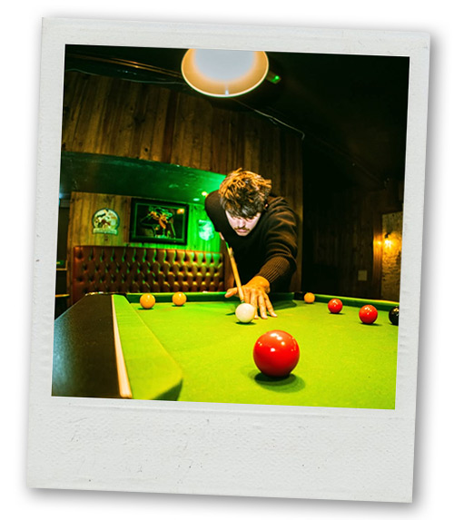 A Polaroid of a man trying to hit a red ball on the pool table