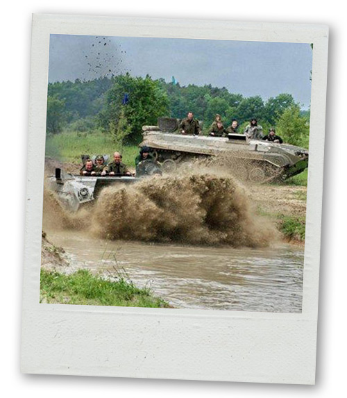 A Polaroid of two groups of men riding a tank whilst mud flies everywhere