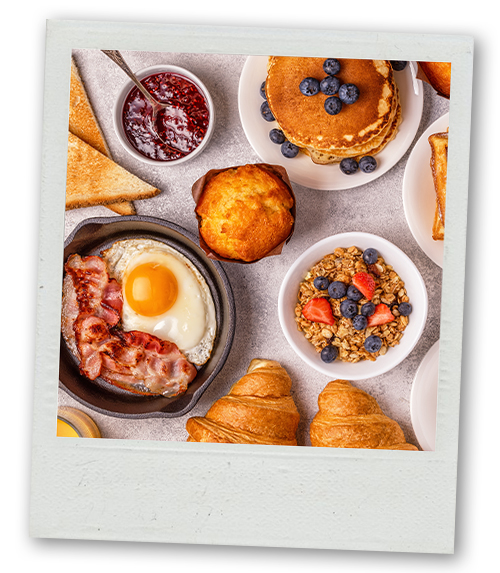 A Polaroid of a selection of brunch dishes including pancakes, pastries and cereal