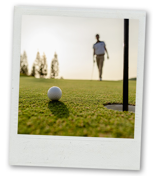 A Polaroid of a golf ball sat right next to a hole with a golfer in the background