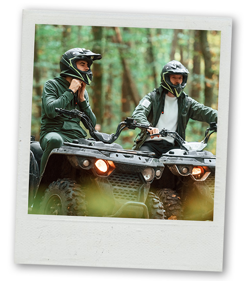 A Polaroid of two men quad biking through the forest