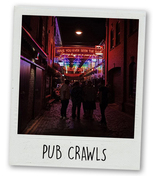 A Polaroid of some people on a bar crawl on a street in Belfast lit up at night which has the caption Pub Crawls