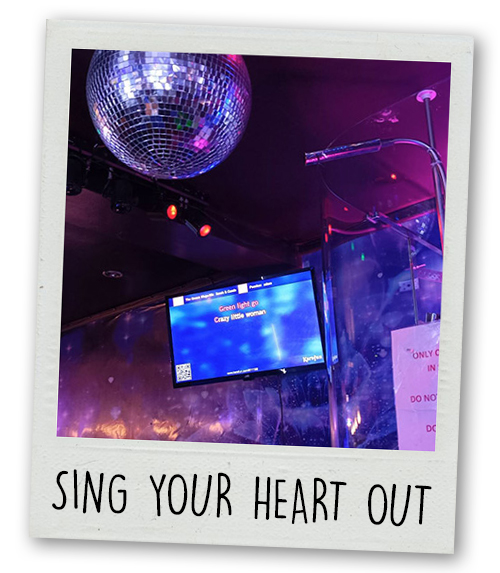 A Polaroid of the shower karaoke at the River Rooms with the caption Sing Your Heart Out