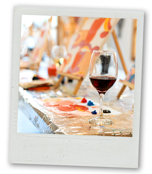 A Polaroid of a bunch of painting easels sat next to a glass of wine