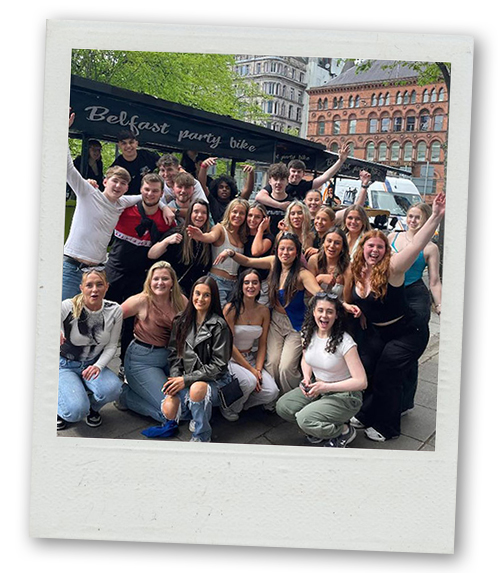 A Polaroid of a mixed gender group posing in front of the Belfast Pedi Bike