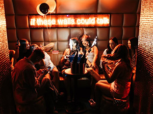 A hen group in a club that has a neon sign reading if these walls could talk 