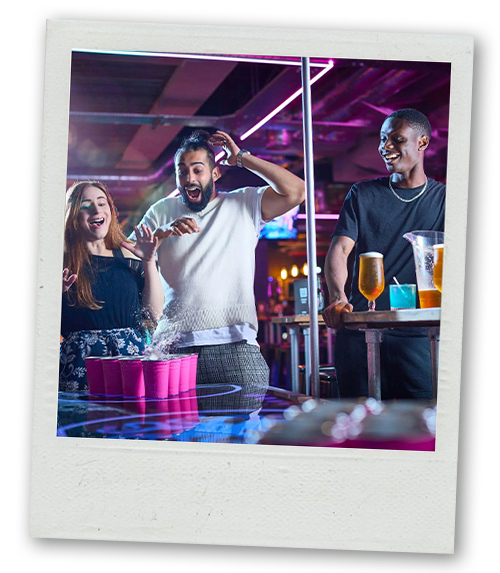 A Polaroid of group of people playing beer pong