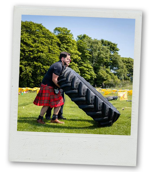 A Polaroid two men trying to pick up massive tyres