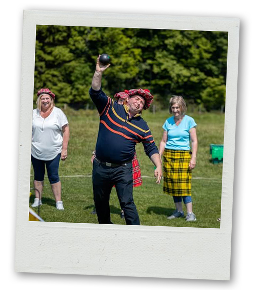A Polaroid of a man about to throw a shot put whilst several women watch on
