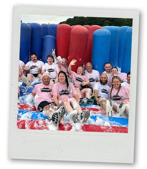A Polaroid of a group of people sat on a soapy inflatable