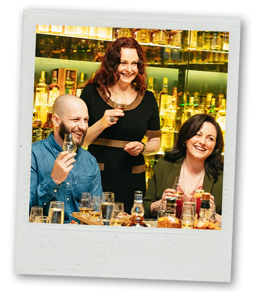 A Polaroid of two women and a man doing some whisky tasting