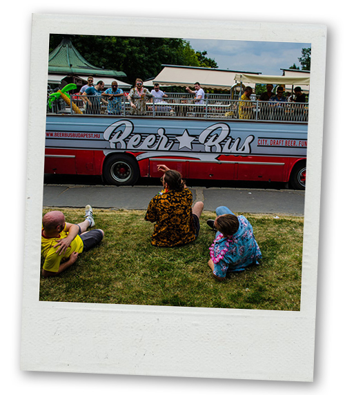 A Polaroid of the beer bus driving by some people relaxing on some grass