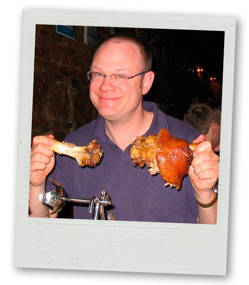 A Polaroid of a man on a stag do eating meat off the bone as part of a brewery dinner