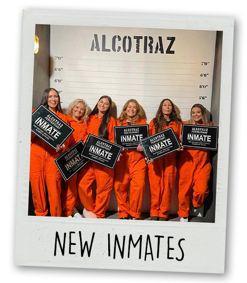 A Polaroid of a hen do group dressed up in orange prison jumpsuits with a line up backdrop with the caption New Inmates