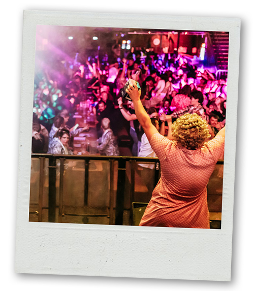 A Polaroid of a woman stood on stage facing a crowd with a bingo prize in her hand
