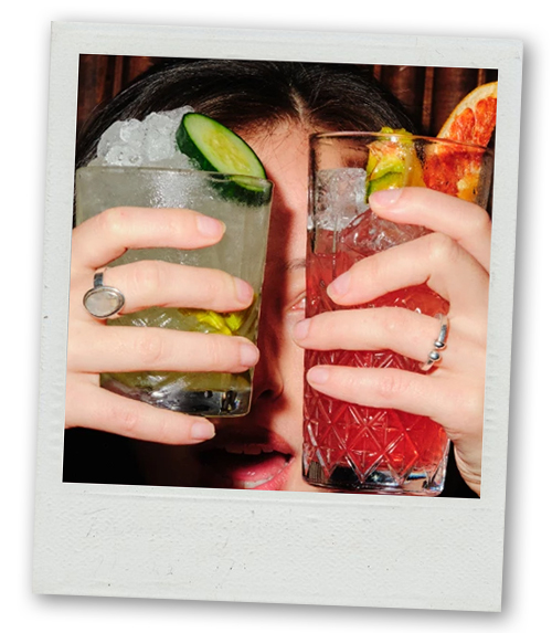 A Polaroid of a woman holding up two cocktails