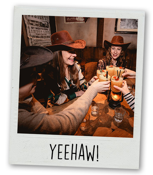 A Polaroid of a hen do group wearing cowboy hats and clinking cocktails with the caption Yeehaw!