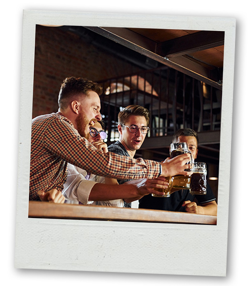 A Polaroid of a stag do group clinking their pints at a bar