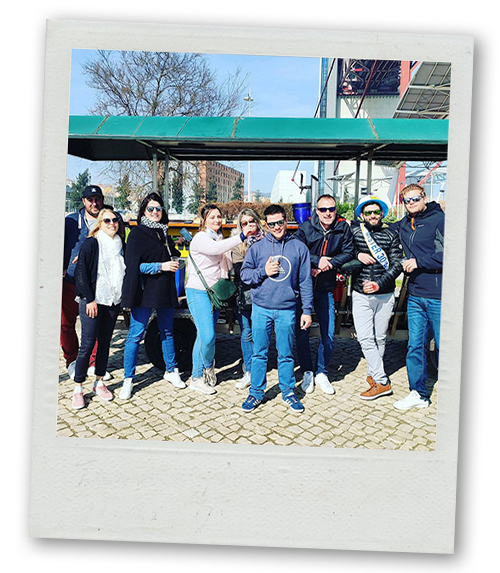 A Polaroid of a mixed gender group posing in front of a beer bike