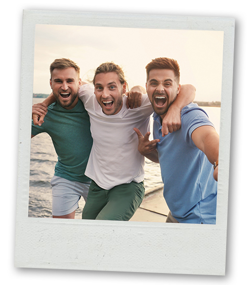 A Polaroid of three men posing for the camera with the sea in the background