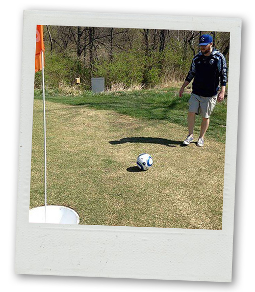 A Polaroid of a man about to kick a football towards a golf hole during a game of footgolf