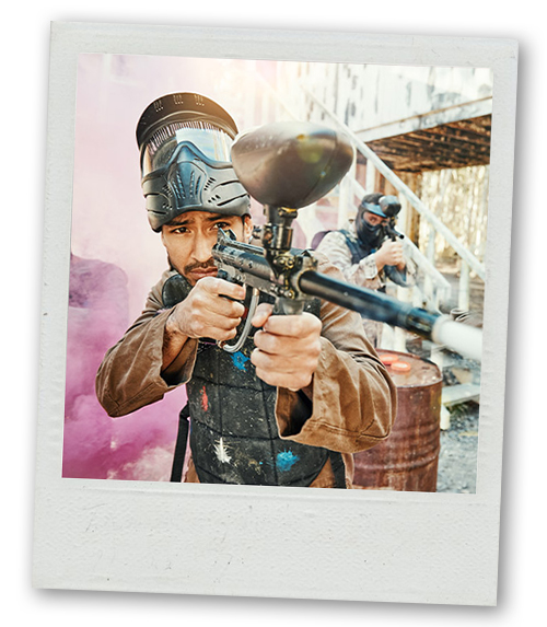 A Polaroid of a man aiming a paintball gun in an outdoor setting