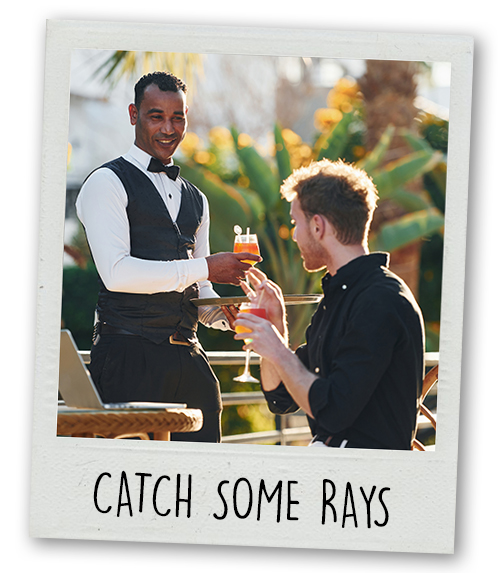 A Polaroid of a waiter in a formal waiter outfit serving a man two cocktails