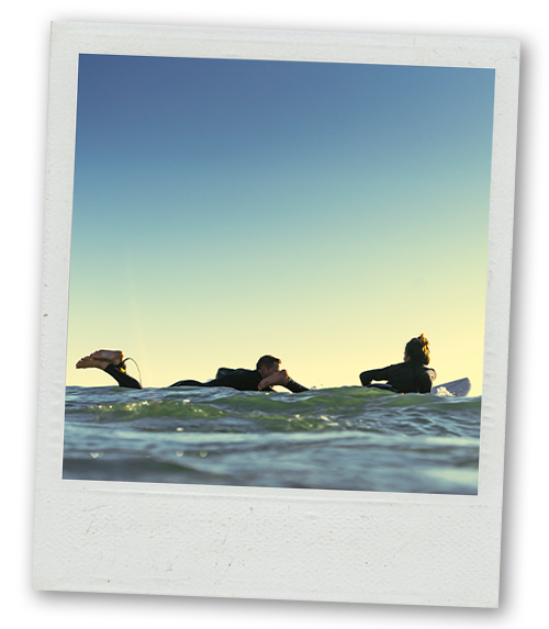 A Polaroid of two people laying on surf boards