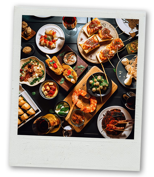 A Polaroid of a large selection of tapas spread out on a table
